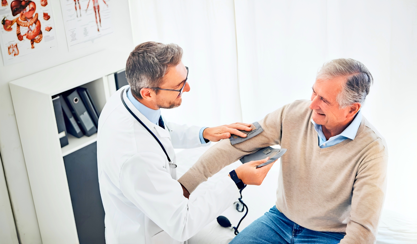 Doctor checks an older man's blood pressure by placing a cuff on his arm in a clinic setting
